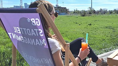 Eine Frau sitzt in einem Liegestuhl und trinkt ein Glas Limonade.