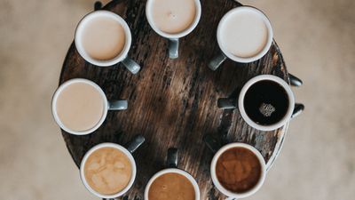 verschieden gefüllte Kaffeetassen auf einem Holztisch