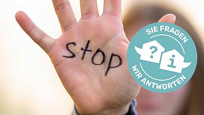 Frau die Hand mit Stop-Schriftzug auf der Handfläche in die Kamera hält.