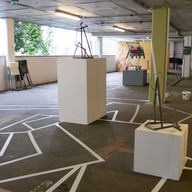 Geschoß eines leeren Parkdecks mit grafischem Muster aus Klebeband am Boden und weißen Podesten