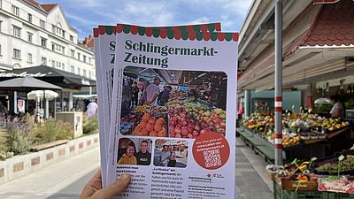 ein Magazin mit Titel Schlingermarktzeitung, im Hintergrund Obststand und Grün