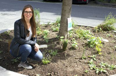 bepflanzte Baumscheibe mit einer sitzenden Damen im Vordergrund