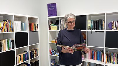 Lesende Frau vor Büchertauschregal