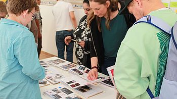 Menschen betrachten Fotos und Scrap-Books der Ausstellung "Sprachen in Bildern"