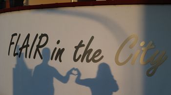 Unter dem Schriftzug "Flair in the city" sind die Schatten von zwei Menschen zu sehen, die mit ihren Händen gemeinsam ein Herz formen