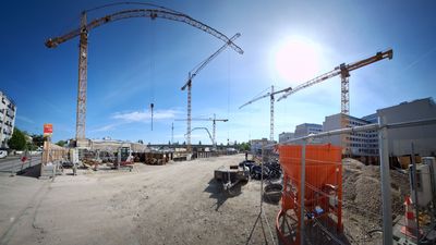 Eine Baustelle mit Kränen, auf der neue Wohnungen entstehen.