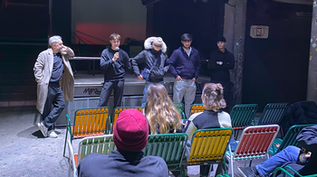 Personen mit Mikrofon sprechen vor einem sitzenden Publikum.