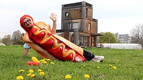 Eine Person, verkleidet als Hotdog lädt freundlich zum Nachbarschaftstreffen.