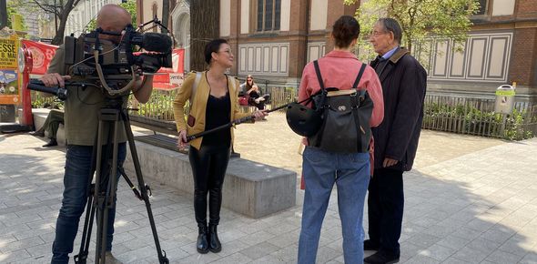 ein älterer Herr in schwarzer Kleidung wird von einer Dame interviewt, ein Mann mit Kamera und eine Dame mit Mikrofon ist zu sehen