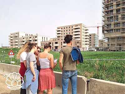 vier Personen stehen vor hohen Gebäuden in Bau