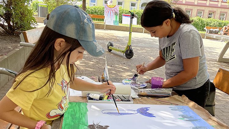 Zwei Kinder malen mit Wasserfarben im Park