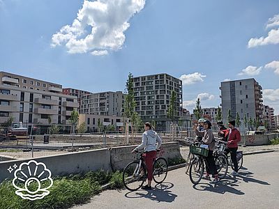 Personen draußen mti dem Fahrrad, betrachten Gebäude