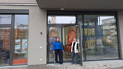 2 GB*Mitarbeiter*innen stehen in der offenen Tür des GB*Stadtteilmanagement-Lokals