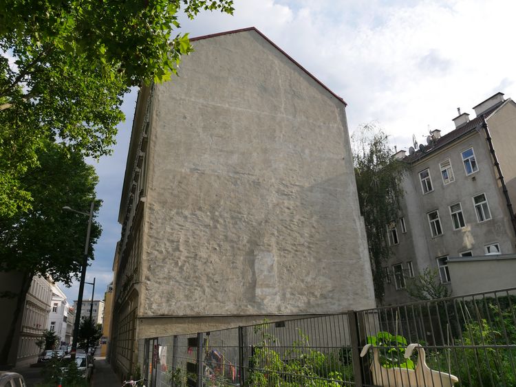 Große graue Feuermauer eines vierstöckigen Gründerzeithauses