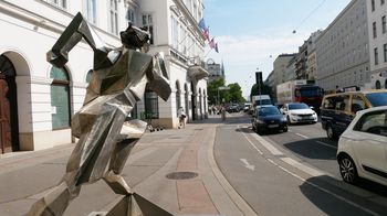 Blick entlang einer Straße, im Vordergrund eine metallerne Skulptur eines Läufers