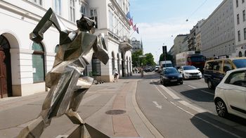 Blick entlang einer Straße, im Vordergrund eine metallerne Skulptur eines Läufers