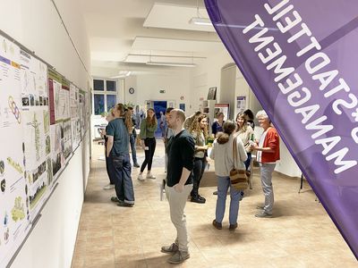 Menschen in einem Raum, die miteinander reden und Plakate anschauen