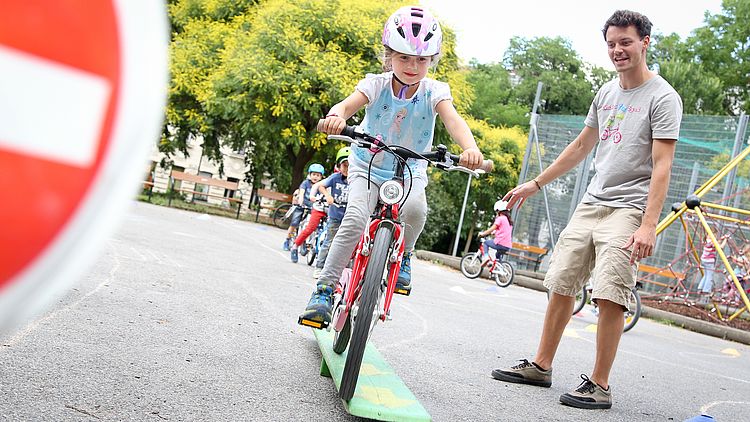 Kind mit Fahrrad fährt über einen Parcours