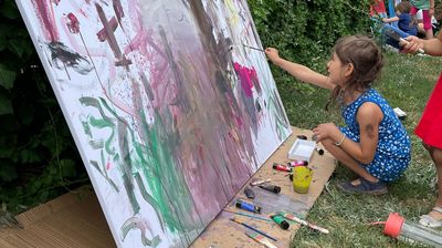 Nachbarschatz Malworkshop Ein Kind malt im Park auf eine Leinwand