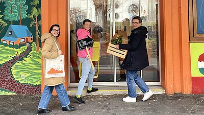 Drei Personen mit Kisten bepackt gehen in das neue Stadtteilbüro.