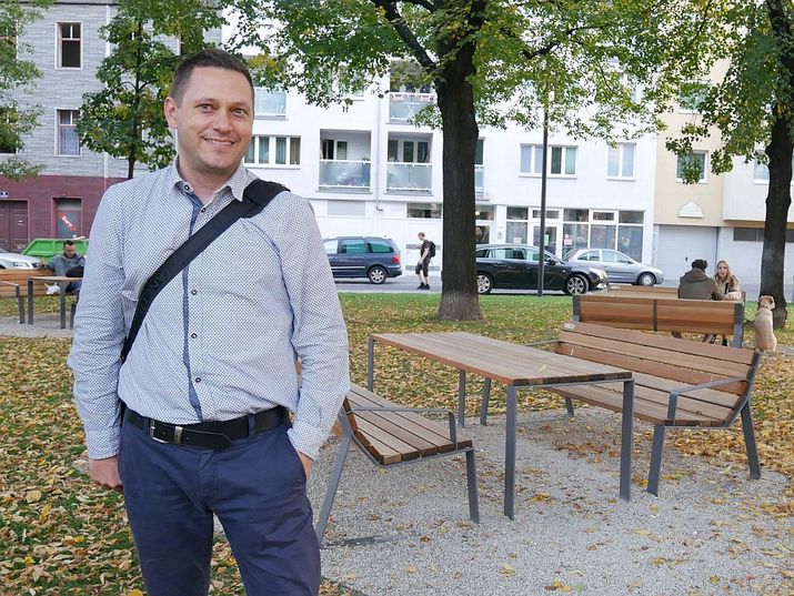 Ein Besucher am Johann-Nepomuk-Berger-Platz, im Hintergrund neue Parkmöbel und ein Baum