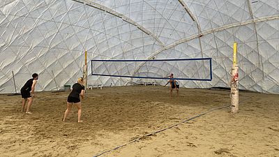 4 Personen spielen Beachvolleyball in einer Halle.