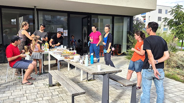Menschen stehen draußen um einen Tisch mit Essen