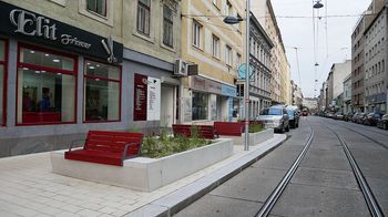 Blick entlang der Neulerchenfelder Straße mit neuer Gehsteigvorziehung und weinroten Bänken.