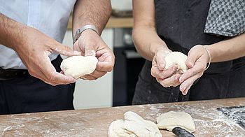 Vier Hände, die einen Brotteig formen