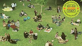 Auf einer Wiese sitzen Leute und haben ein Picknick