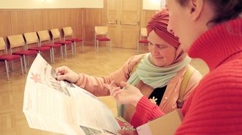Zwei Personen schauen interessiert in ein aufgefaltetes Faltblatt.