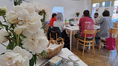 Die 8 Mitglieder des Grätzlrats sitzen um den Tisch und beraten über die eingereichten Ideen. Im Vordergrund sieht man Blumen und Schnittlauchbrote als kulinarische Verpflegung.