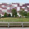 Blick aus einem Park auf ein großes neues Wohngebäude mit rosa Balkonelementen