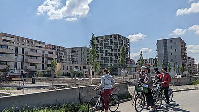 Personen draußen mti dem Fahrrad, betrachten Gebäude