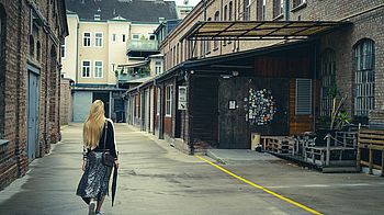 Person von hinten vor Lagerhallen 