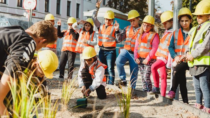 Schulklasse bei Baustellenführung, gelbe Helme