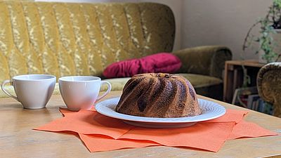 2 Tassen und ein Gugelhupf auf einem Tisch