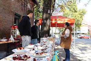 Tisch mit Kuchen im Freien, Personen stehend