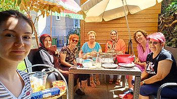 7 Frauen sitzen auf der Terrasse und frühstücken gemeinsam.