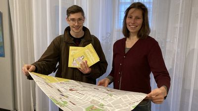 2 Personen halten mehrere Exemplare des Kinderstadtplan Favoriten in Händen.