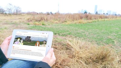 Eine Person sitzt mit einem Tablet in der Hand und schaut sich die Lebendige Stadtteilkarte online an.