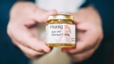 zwei Hände halten ein kleines Honigglas in die Kamera