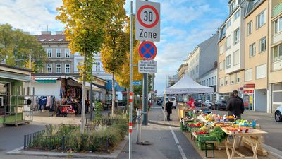 Bauernmarkt Herbstlich verfärbte Bäume und Marktstände auf einem Platz, Sonnenschein und blauer Himmel