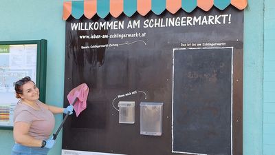Sarah, eine Mitarbeiterin der Gebietsbetreuung, putzt die Markttafel am Schlinermarkt.