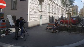 Frau sitzt auf einer Bank und wird von Kamerateam gefilmt