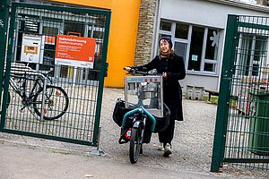 Frau sitzt auf E-Lastenfahrrad und fährt.