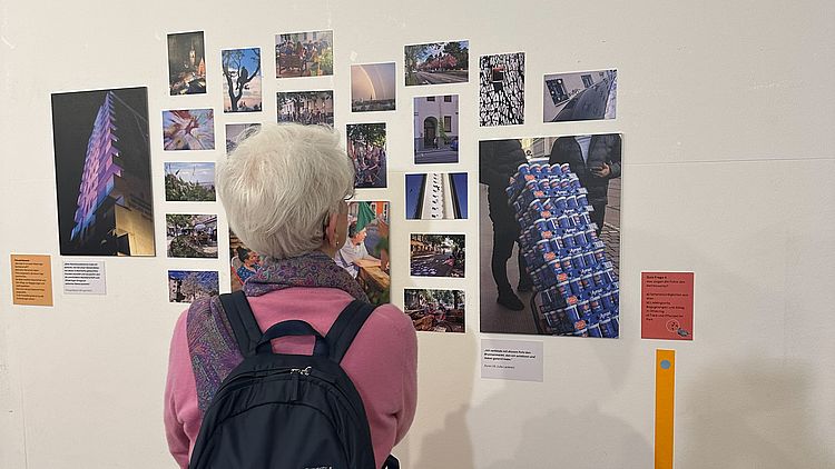 Eine ältere Dame betrachtet Bilder einer Ausstellung.