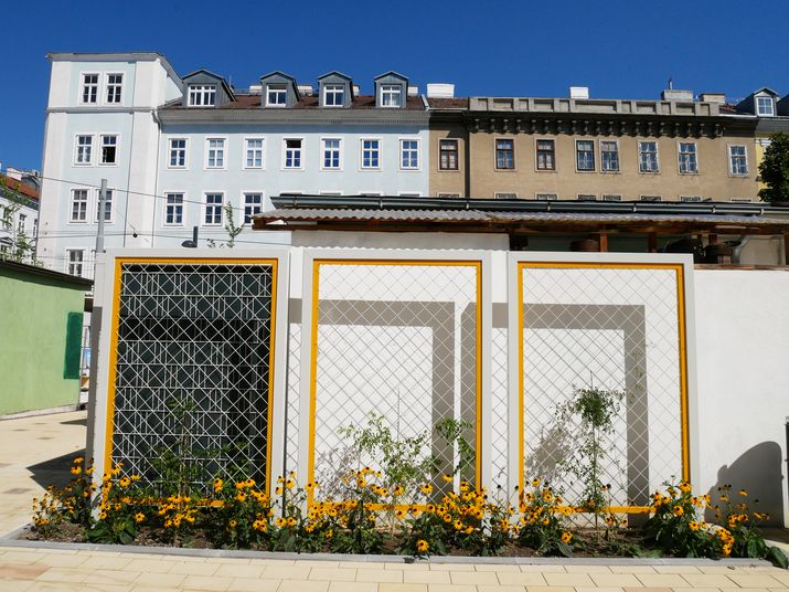 Gelbe Rankgerüste vor weißen Mauern der Marktstände