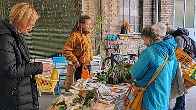 Menschen reden miteinander und begutachten Pflänzchen