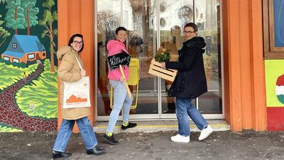 Drei Personen mit Kisten bepackt gehen in das neue Stadtteilbüro.